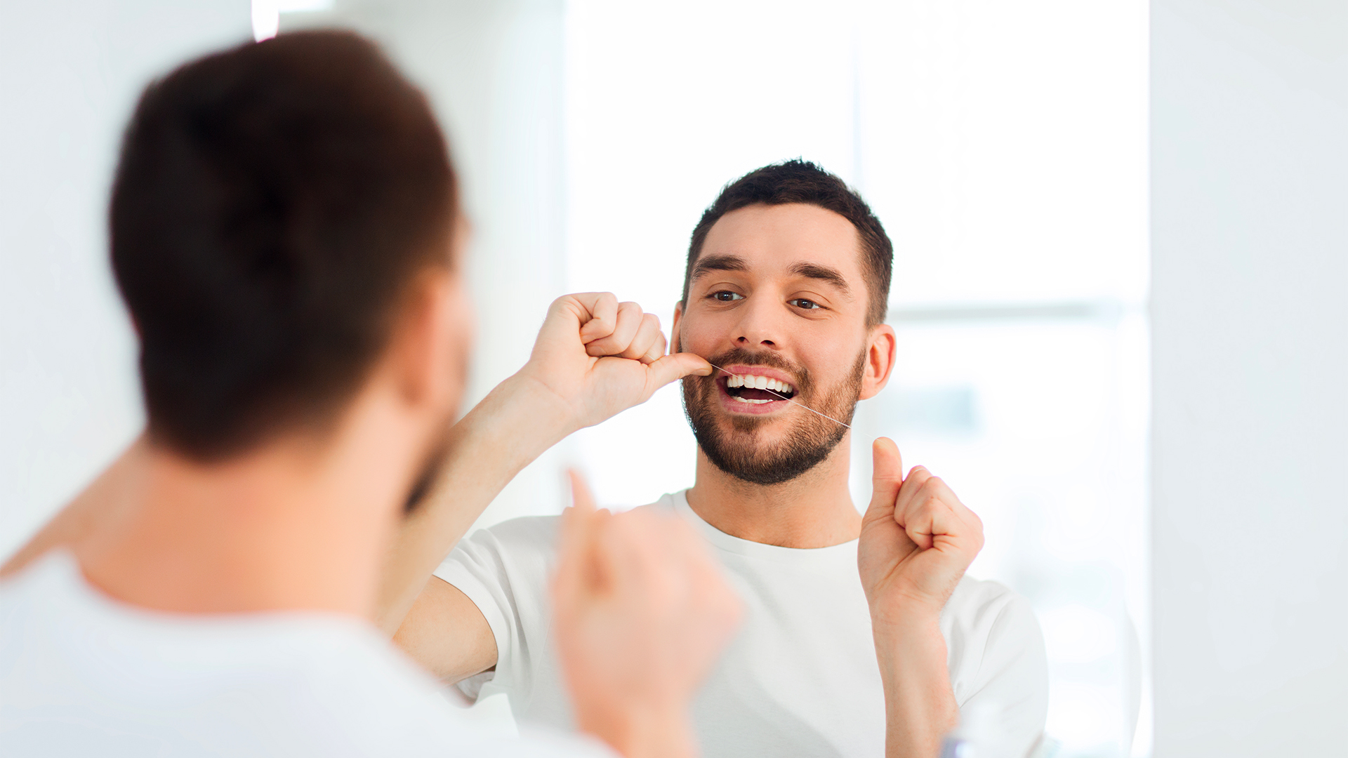 ragazzo usa il filo interdentale sapendo come togliere il tartaro dai denti