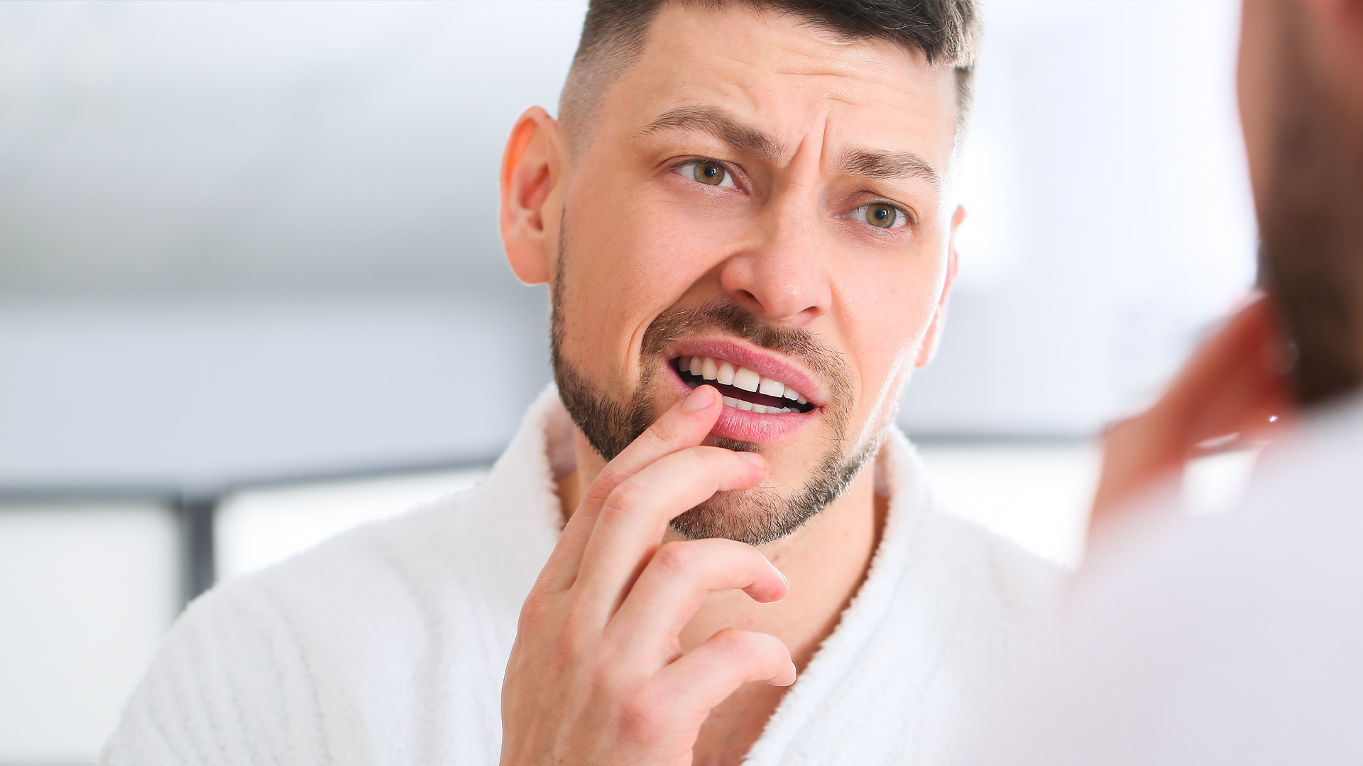 uomo controlla allo specchio di non avere macchie sui denti